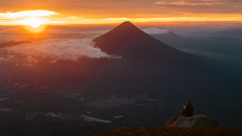 Stunning view of the sunset over Acatenango Volcano in Guatemala, enveloped by clouds.